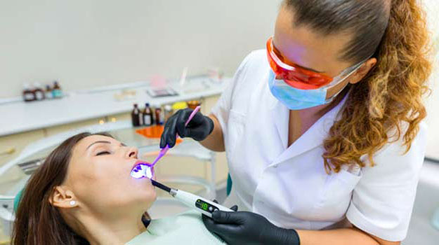 Adult female dentist treating woman patient teeth