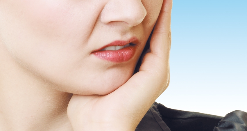 Woman holds her jaw due to pain caused by tooth infection